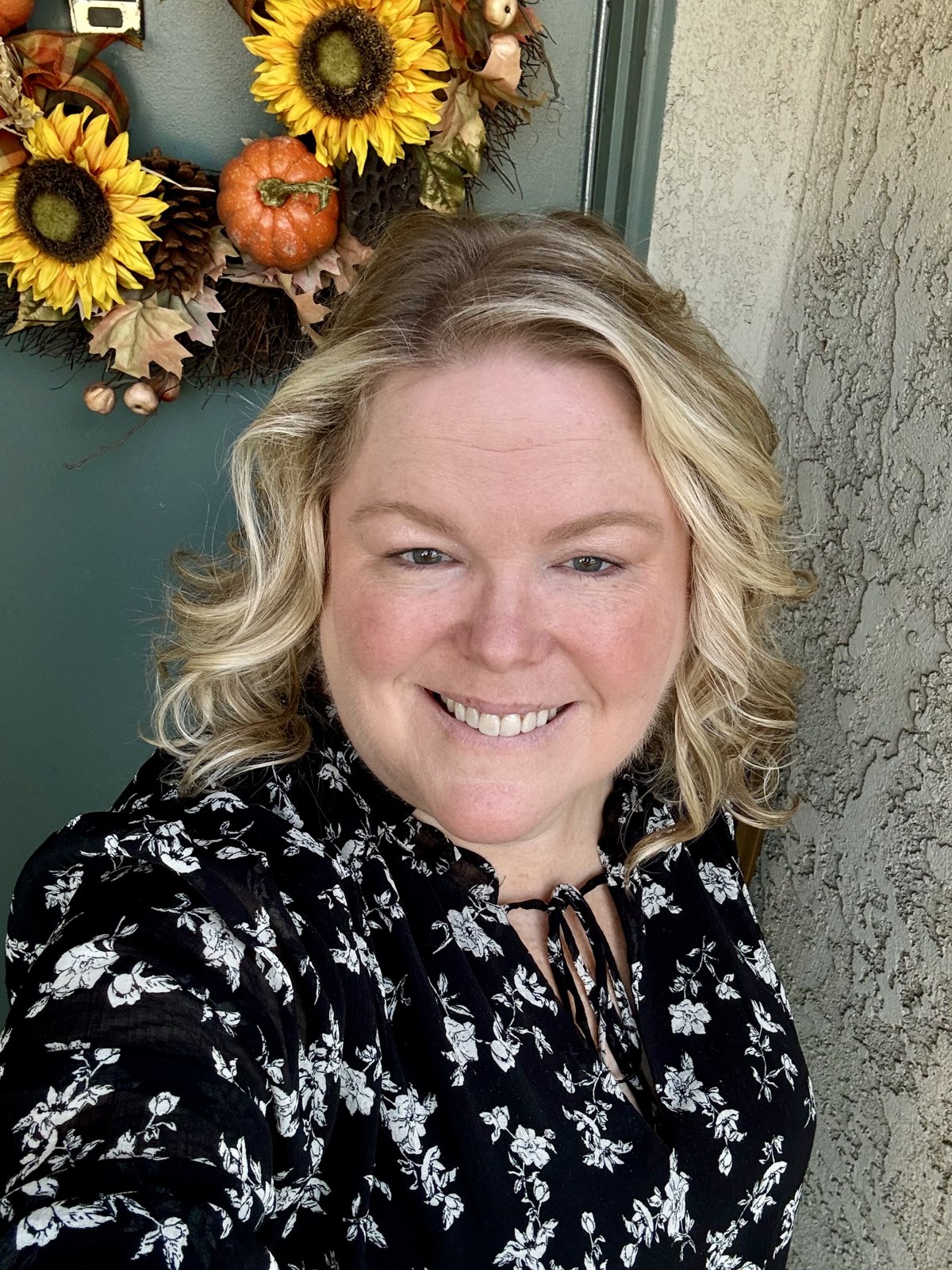 Brooke smiling in front of a sunflower wreath